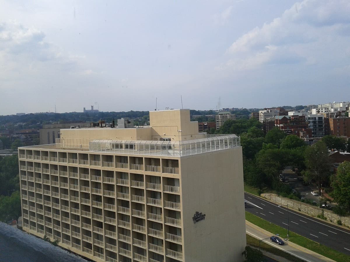 A tall pale residence hall with rows of windows under a blue sky