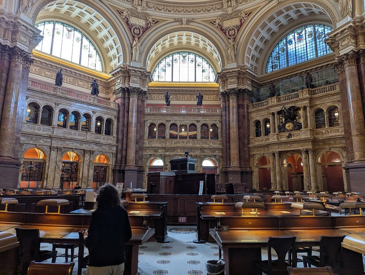 A vast domed reading room with rows of wooden desks