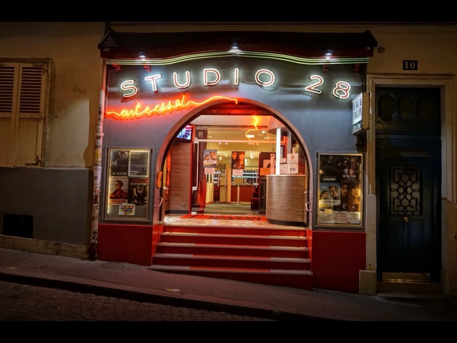 The arched entrance of Studio 28 with a neon sign and red steps, lit at night