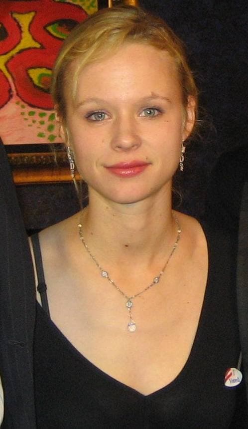 Thora Birch with long fair hair, in black, looking at the camera