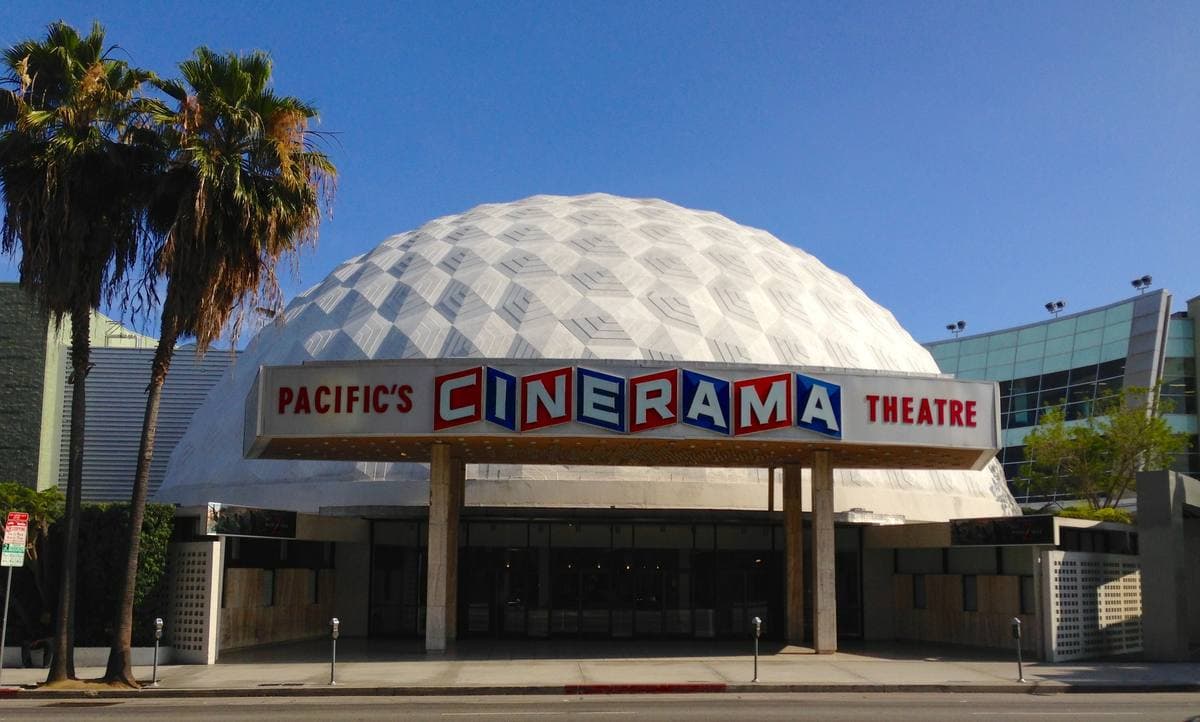 A white geodesic dome cinema behind a glass entrance