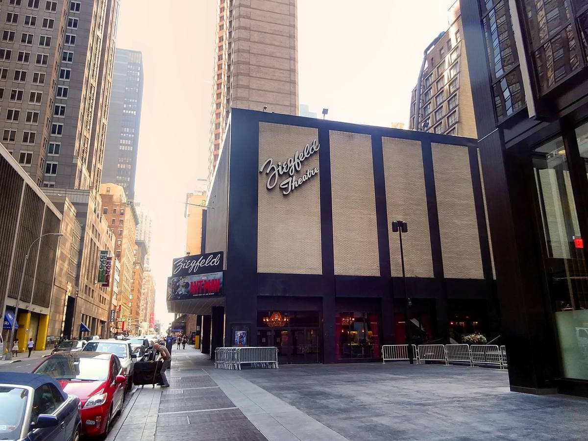 A cinema entrance with a long marquee under a tall office tower