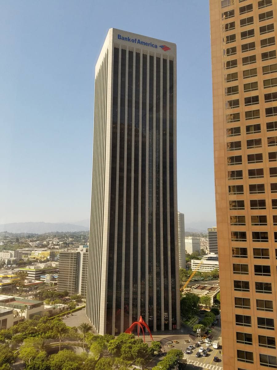 A dark red granite skyscraper rising above downtown Los Angeles