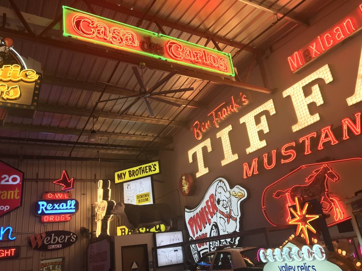 A ceiling crowded with vintage neon and painted business signs
