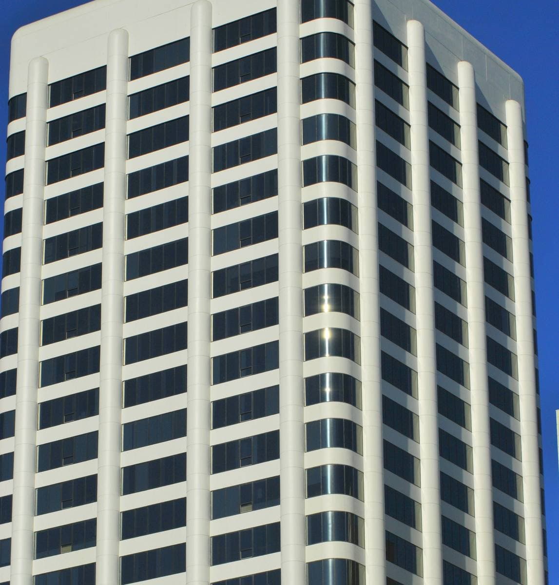 A white mid-century office tower with ribbon windows against blue sky