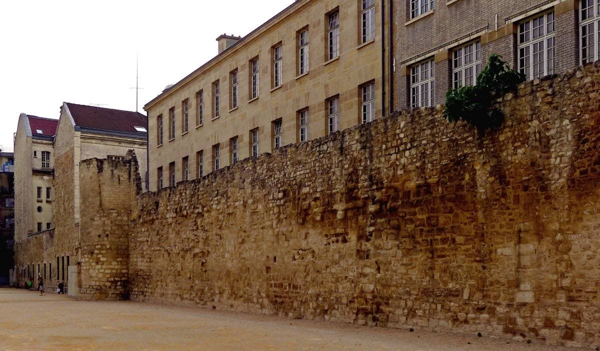 A long rough stone wall in front of a school building