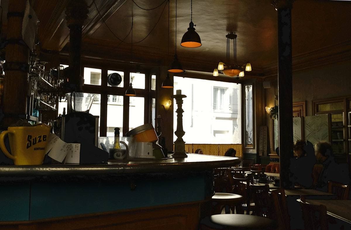 A café interior with a zinc bar, globe lamps and wooden panelling