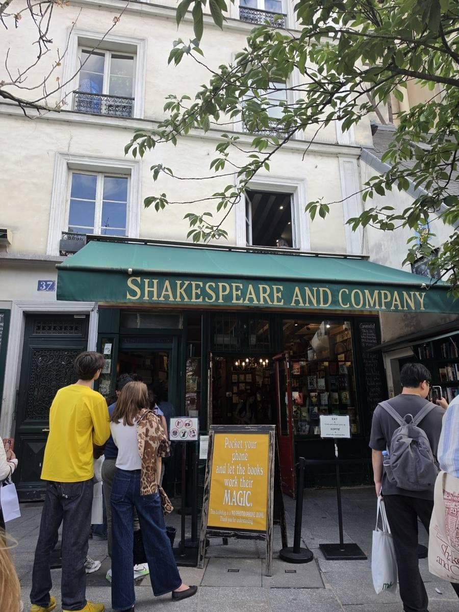 The green and yellow shopfront of Shakespeare and Company, with people at the door