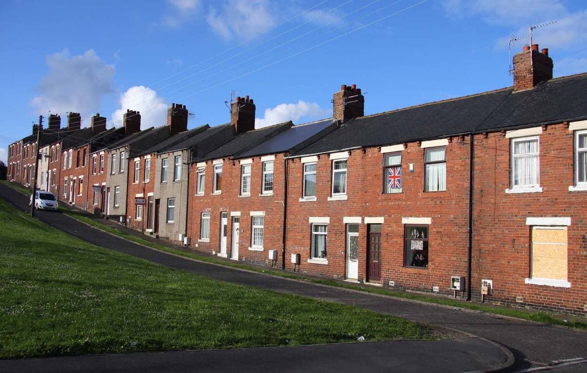 A long red-brick terrace on a slope under a blue sky