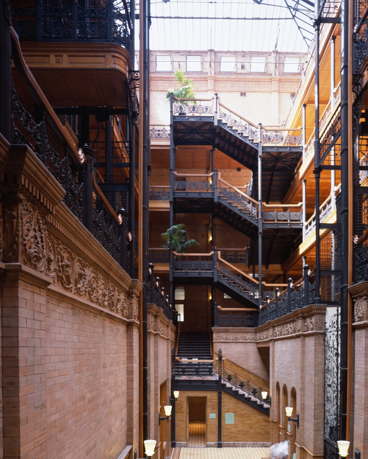 Wrought-iron staircases and balconies rising through a skylit brick court