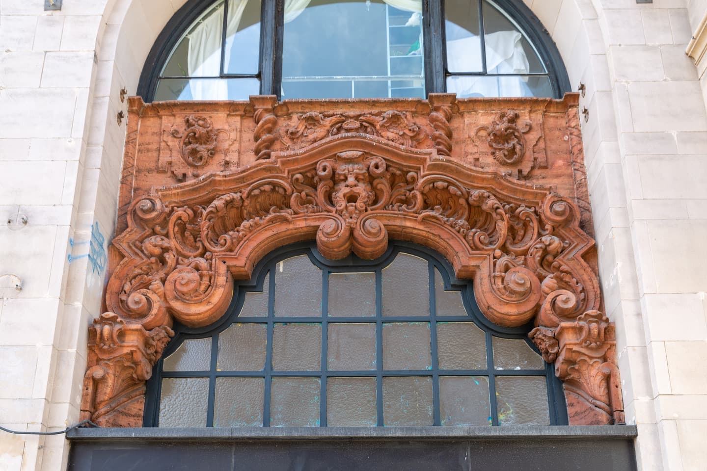 An ornate terracotta-coloured carved arch around an arched window