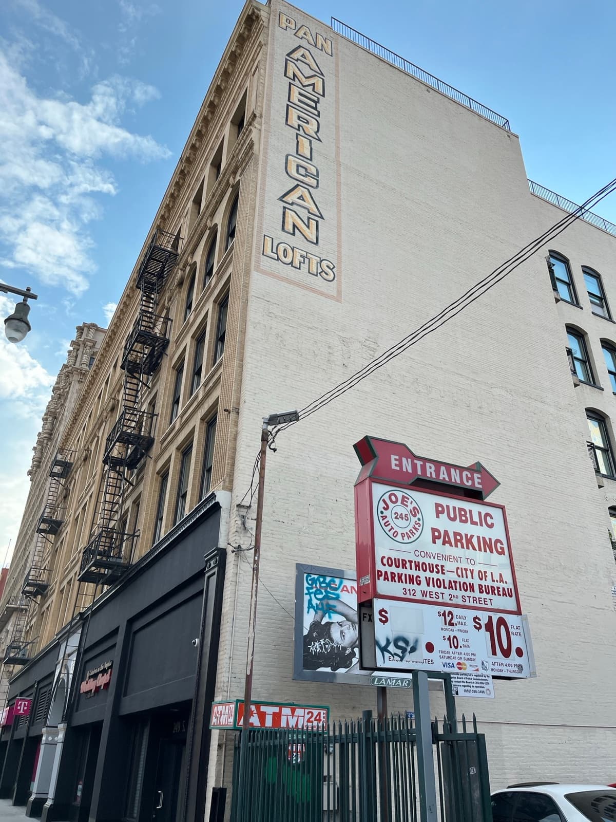 A tall brick building with a vertical Pan American Lofts sign and fire escapes