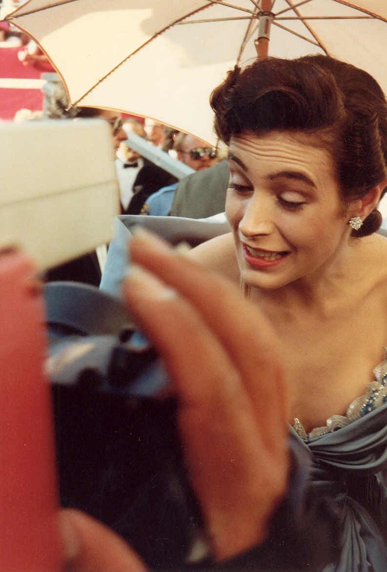 Sean Young with short dark hair, smiling, on a red carpet