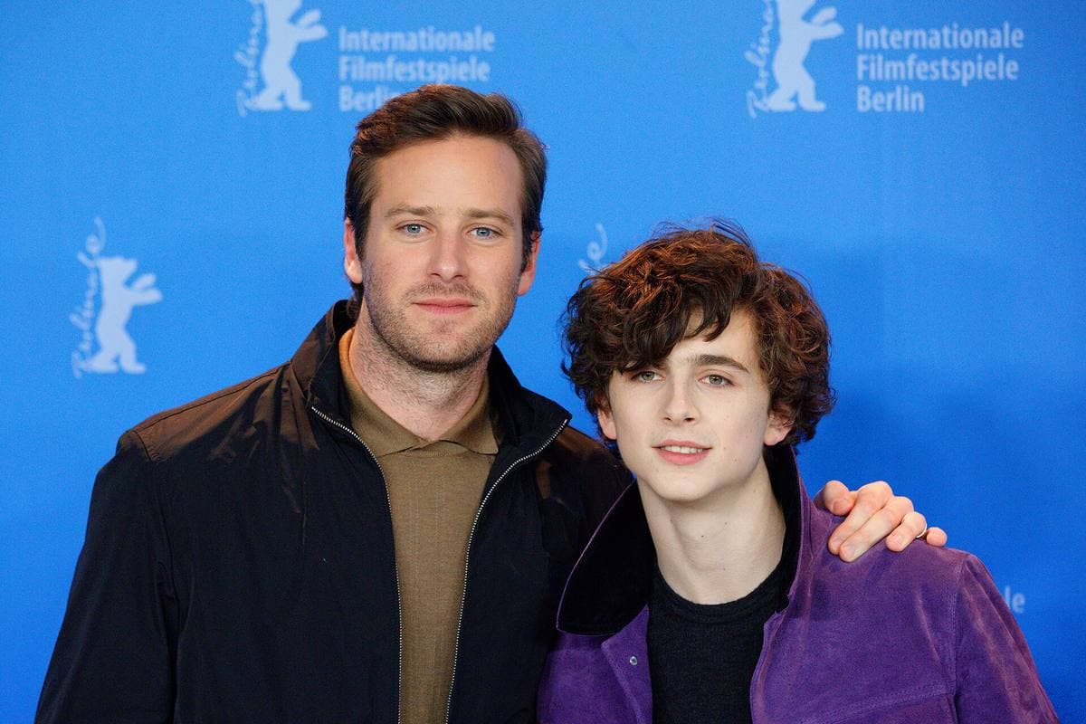 Armie Hammer, his arm round Timothée Chalamet’s shoulders, both smiling in front of a blue Berlinale backdrop