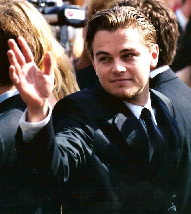 Leonardo DiCaprio in a dark suit and tie, waving to a crowd