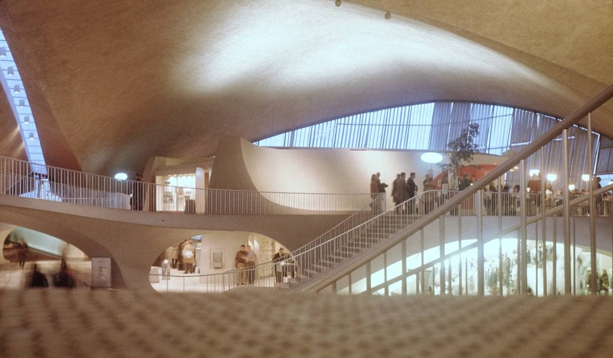 A soaring white concrete interior with curving walls, a staircase and a long window