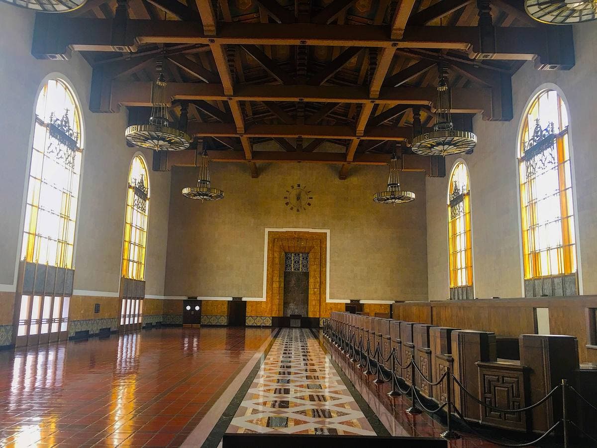 A long hall with a timber-beamed ceiling, tall arched windows and a long wooden counter down one side