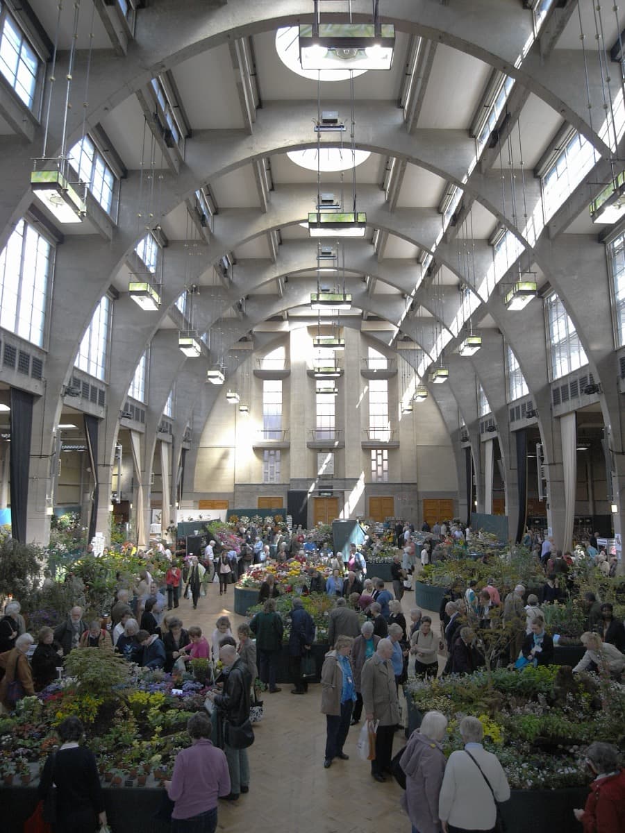 A long exhibition hall with a curved roof, filled with flower displays