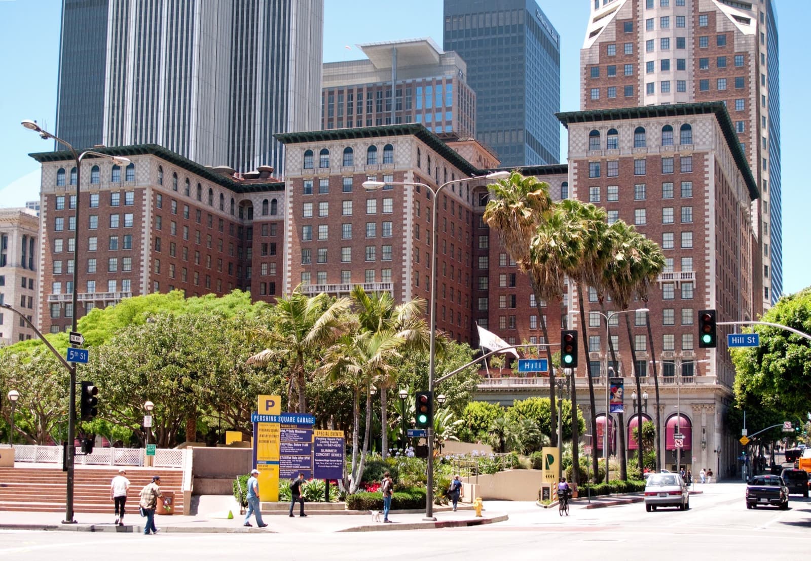 Red-brick hotel towers behind palm trees and a city square