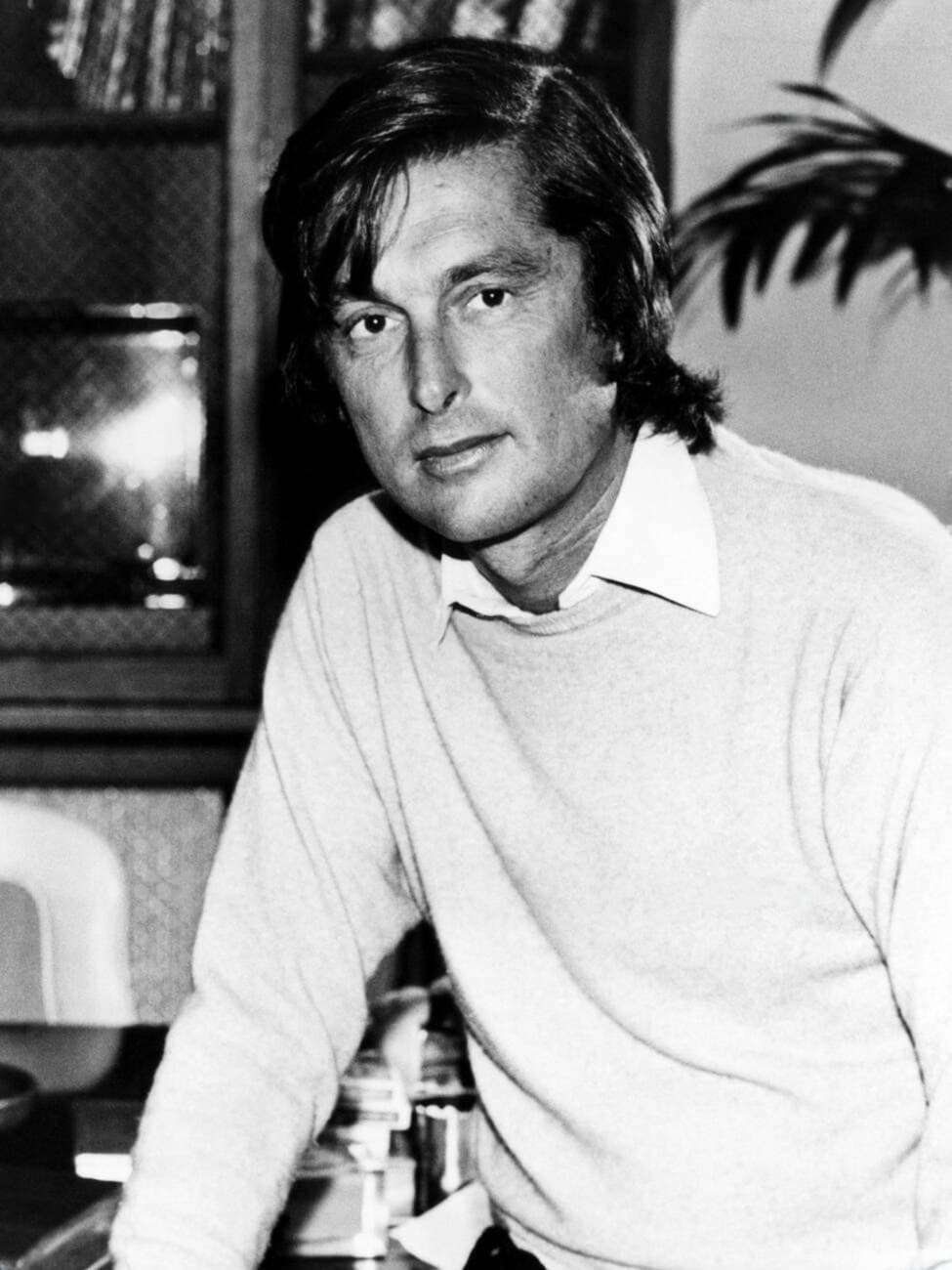 Robert Evans in a white sweater, standing at a counter