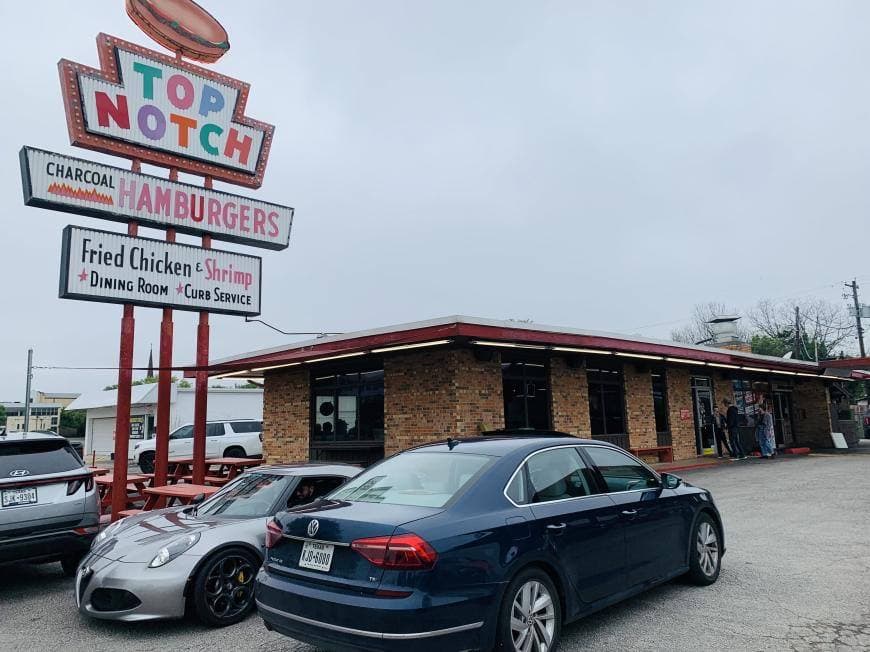 A low brick drive-in with a tall Top Notch sign and cars parked in front