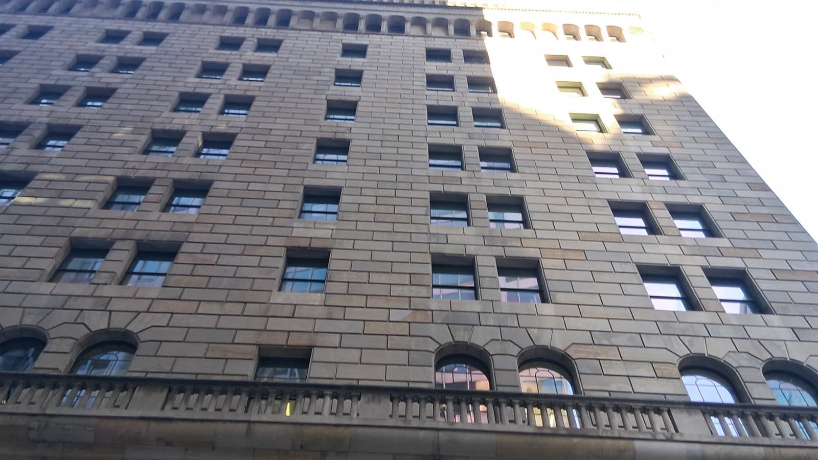 A fortress-like stone bank building with iron lanterns