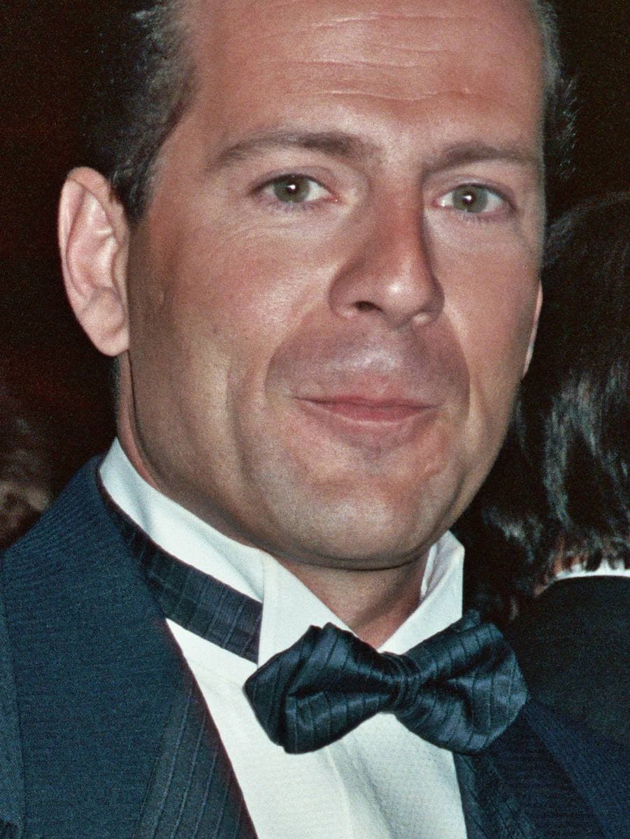 Bruce Willis in a dinner jacket and bow tie, smiling slightly