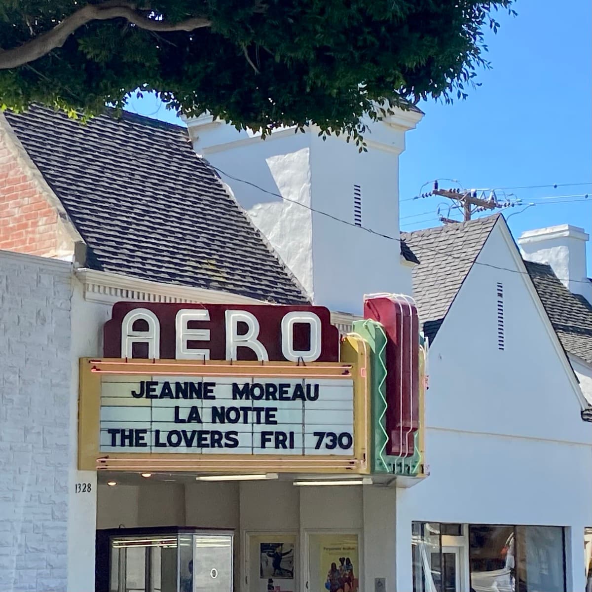 A cinema front with a vertical sign on a city street