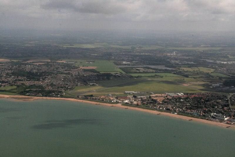 An airfield from above, runways and hangars beside the sea