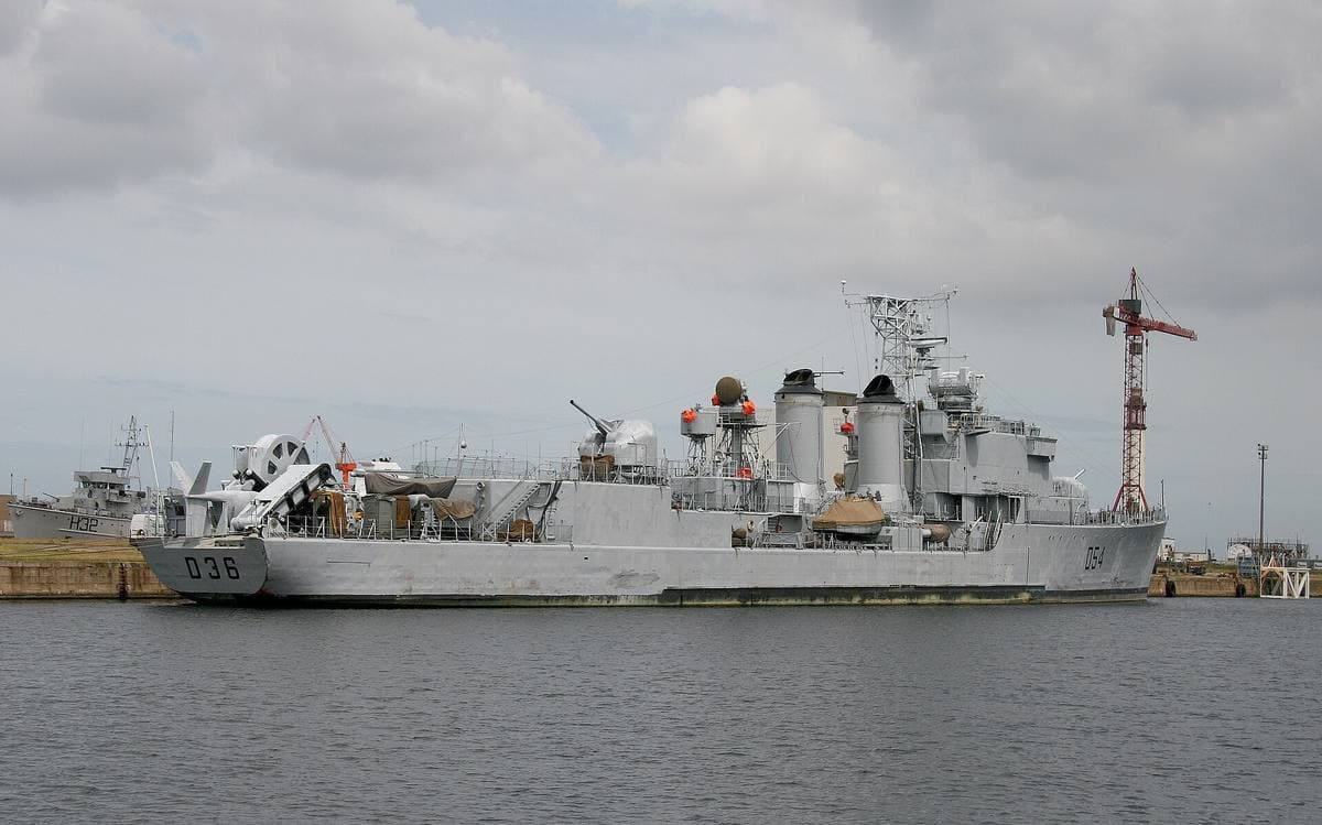 A grey destroyer moored in a harbour, D36 painted on her bow