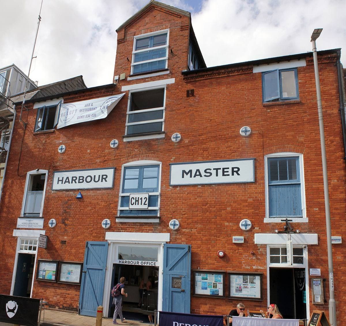 A red-brick harbour building with a Harbour Master sign over a blue door