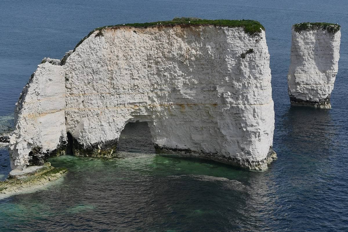 White chalk cliffs and sea stacks above a green-blue sea