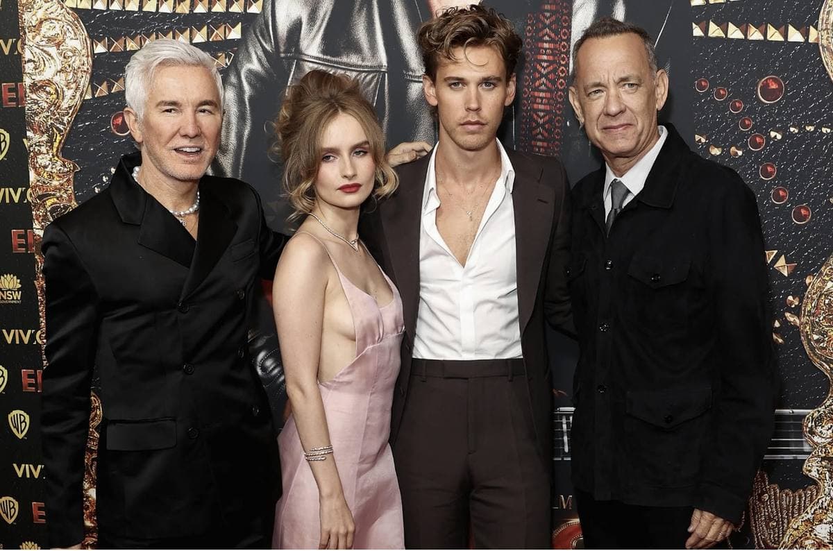 Four people side by side in front of a dark printed backdrop