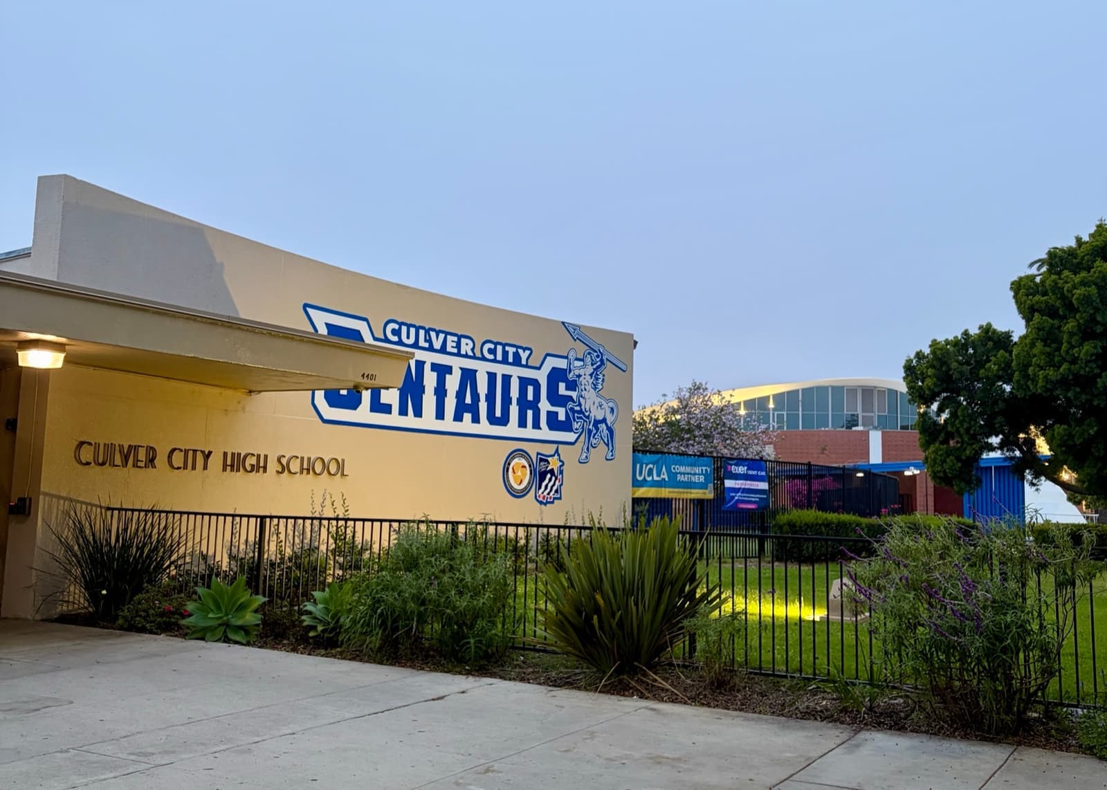 A low school building with a big blue Culver City Centaurs sign and a planted bank in front