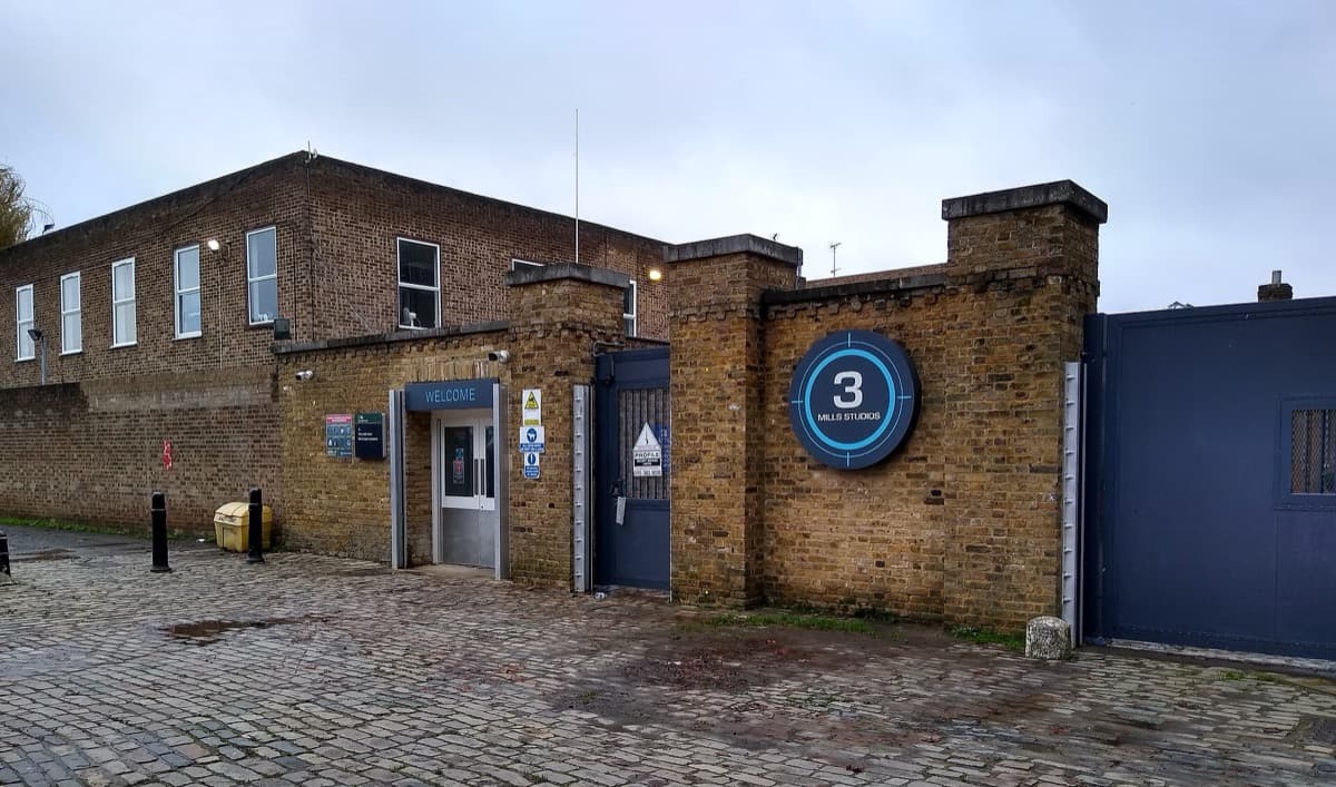 Low studio buildings and a tall cowl on Three Mills Island under a pale sky