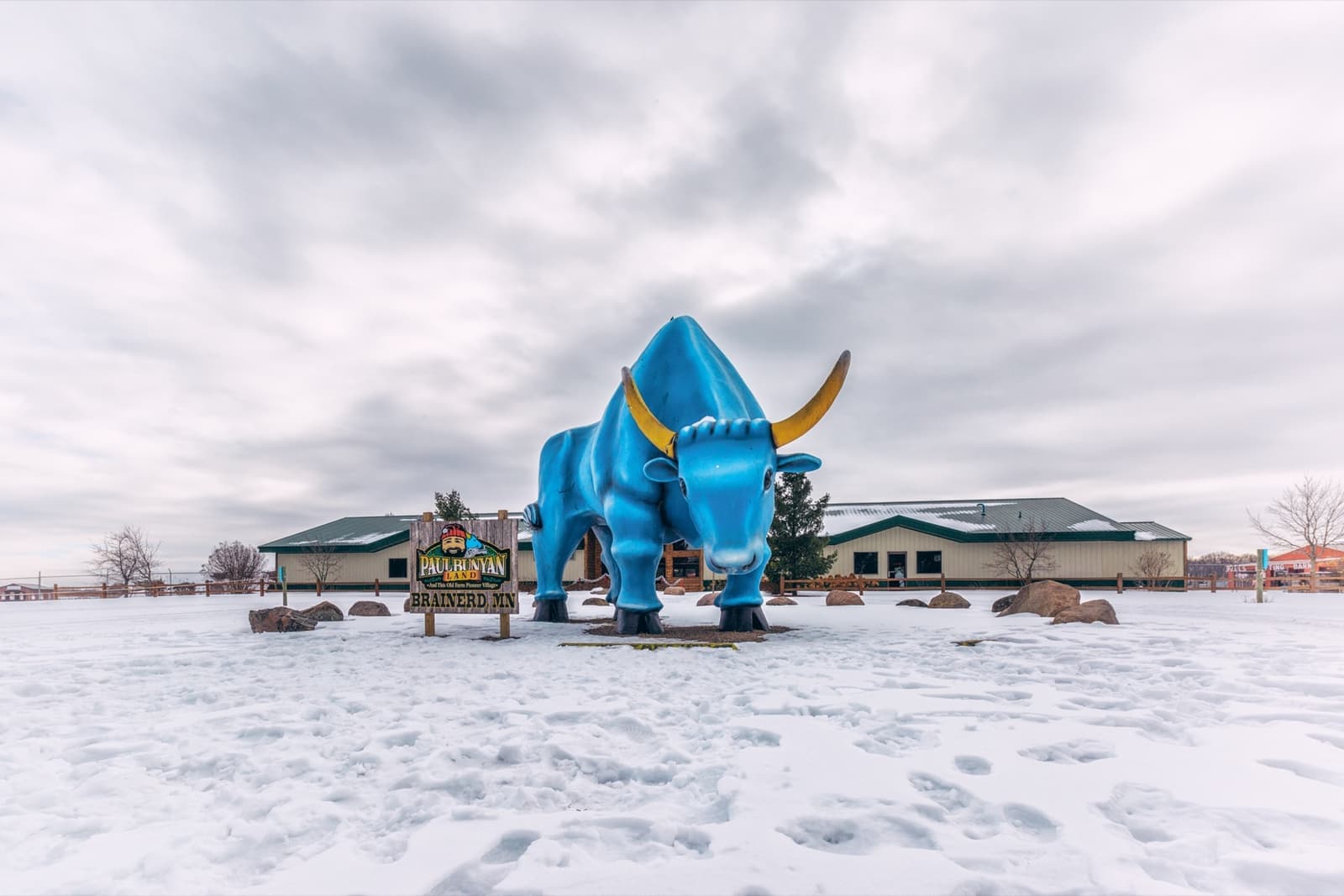 A giant blue ox statue standing in a snowy field under a grey sky