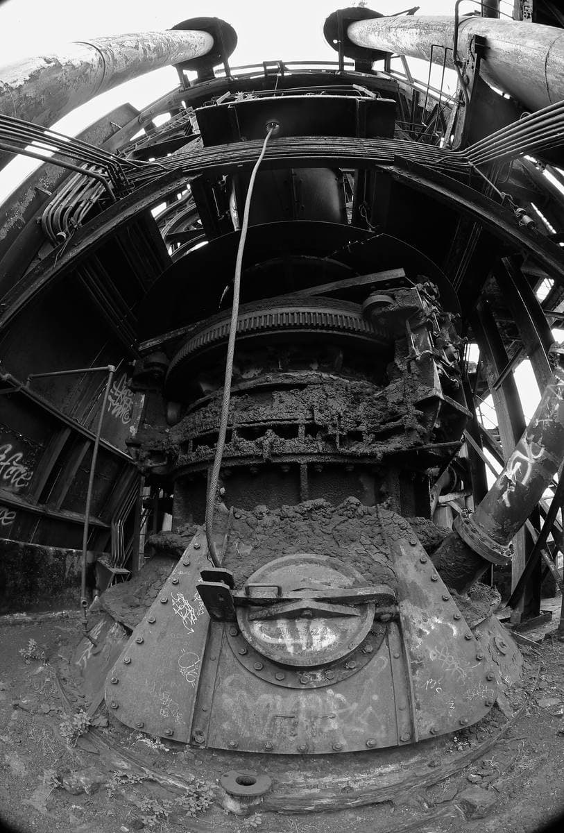Pipes, ducts and the round mouth of a blast furnace in black and white