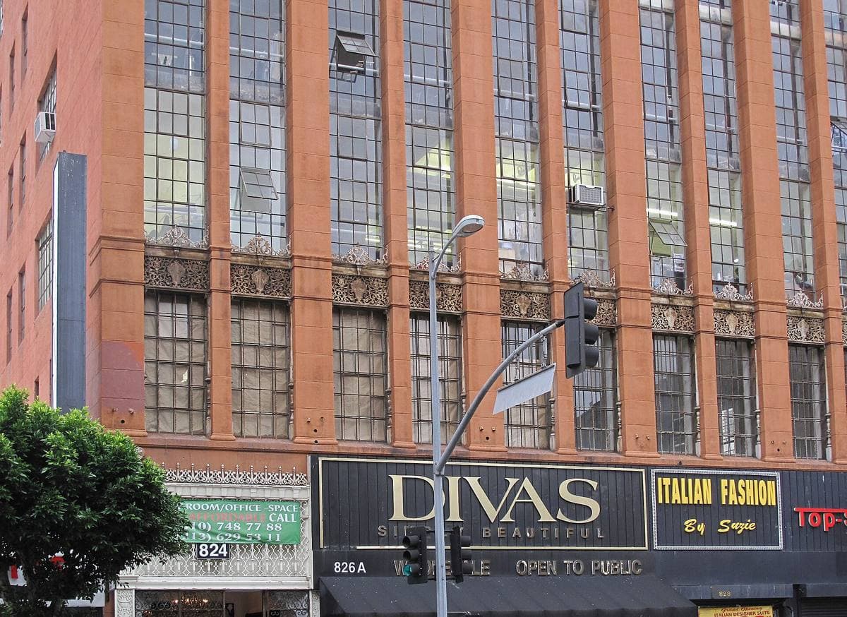 A tall brick industrial building with steel windows over shopfronts on Los Angeles Street