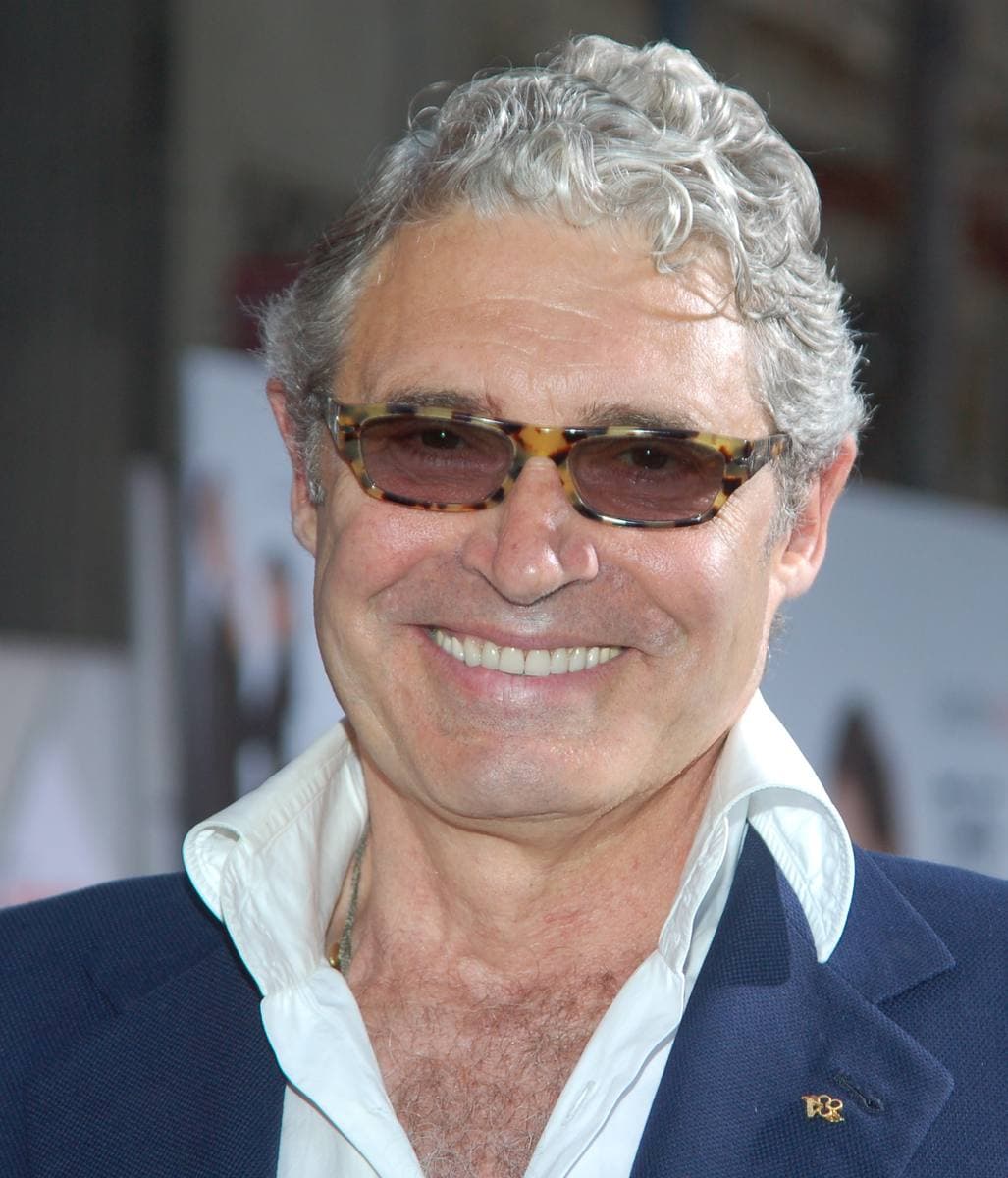 Michael Nouri, grey-haired and smiling, in tinted glasses and a dark jacket