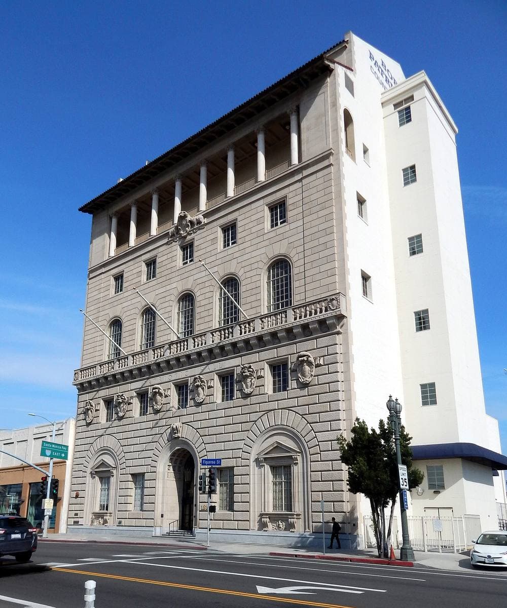A tall pale stone building with arched upper windows on a corner