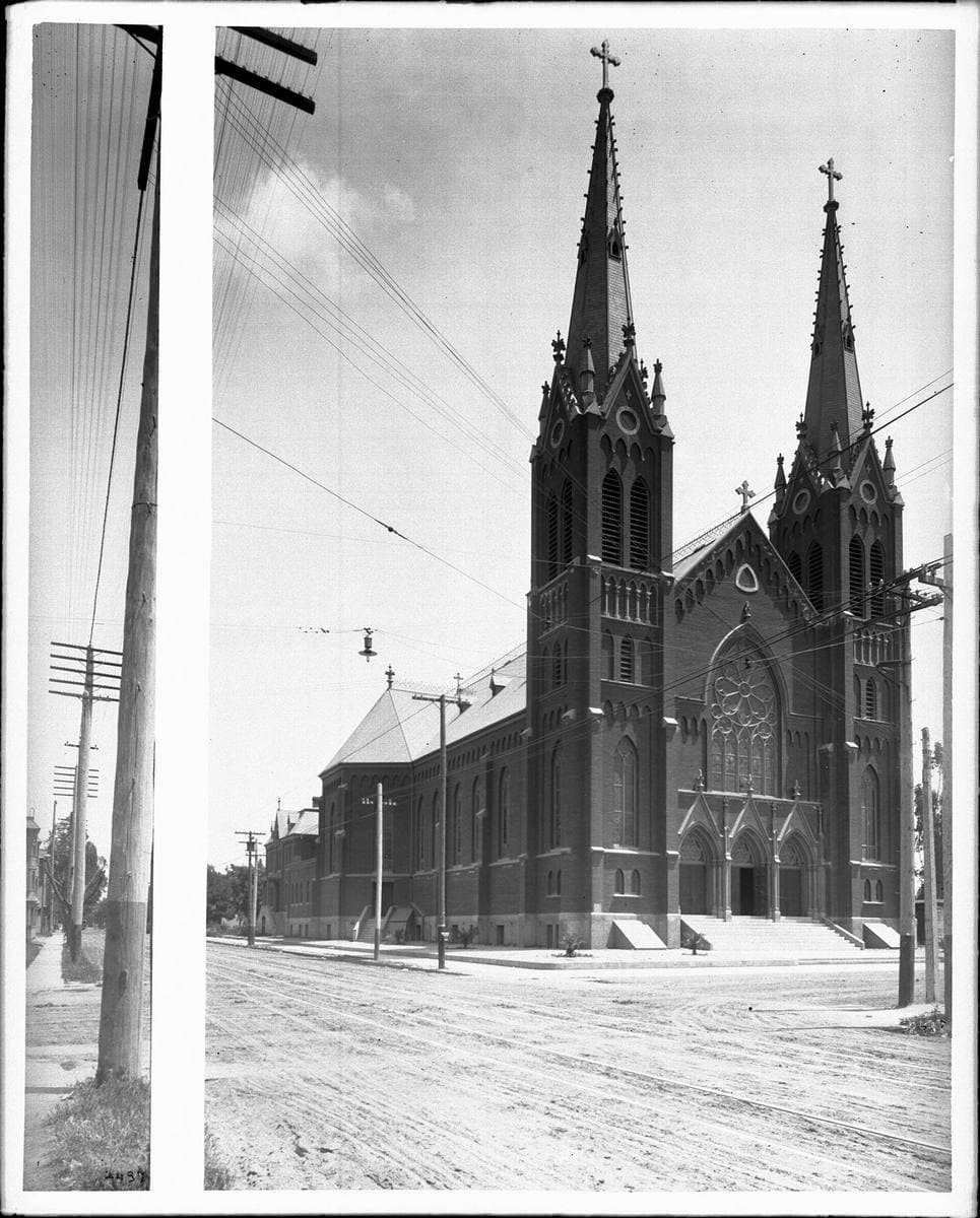 A Victorian Gothic church with twin spires on an unpaved corner
