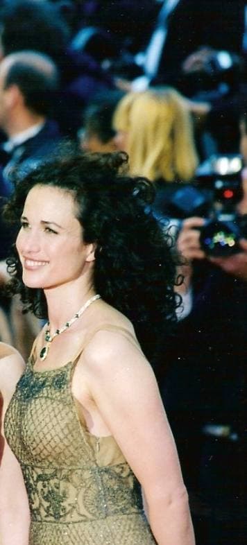 Andie MacDowell with long dark curls in a gold dress on the red carpet