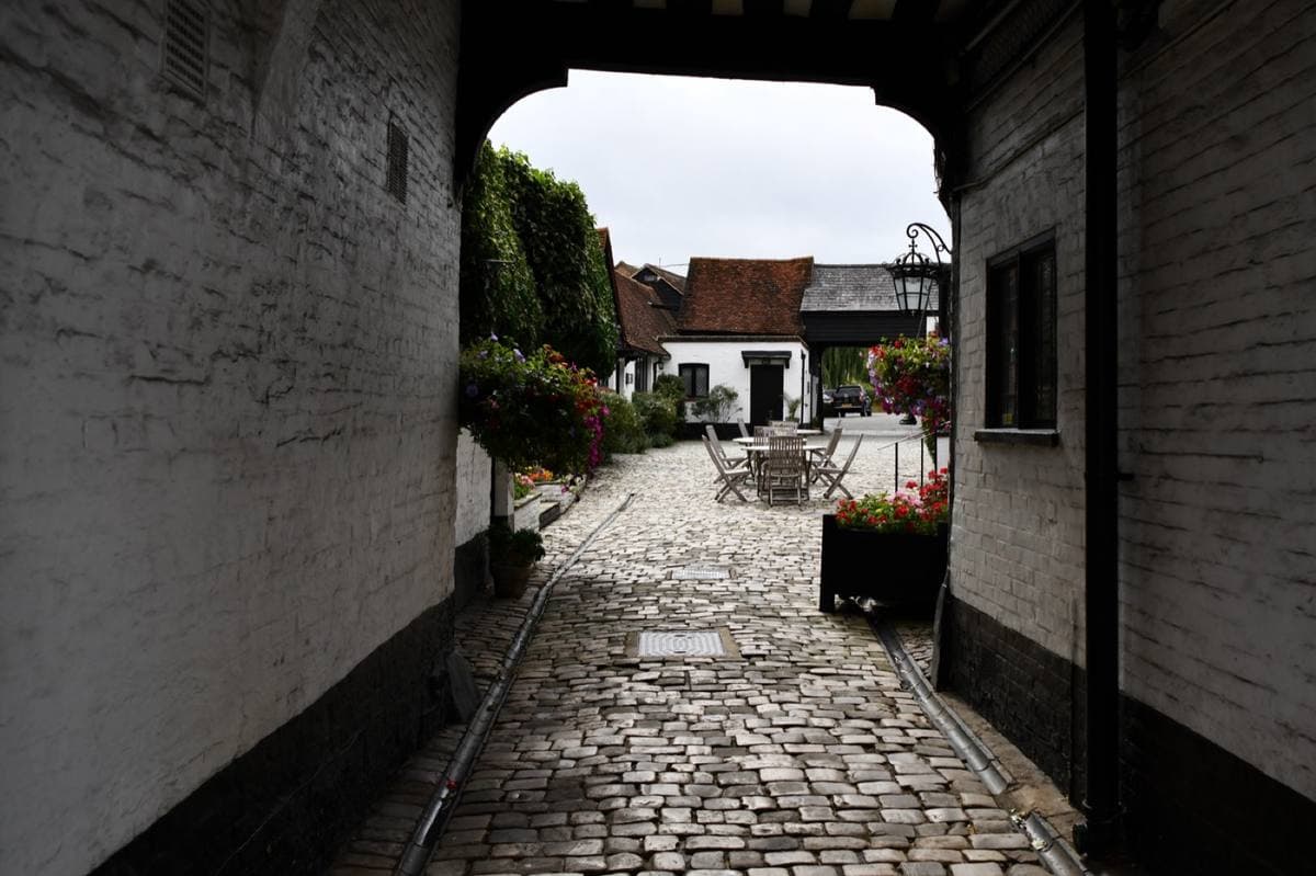 A timbered carriage arch opening on to a cobbled courtyard with flowers
