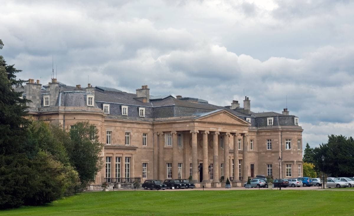 A long pale stone mansion with a columned portico across a lawn