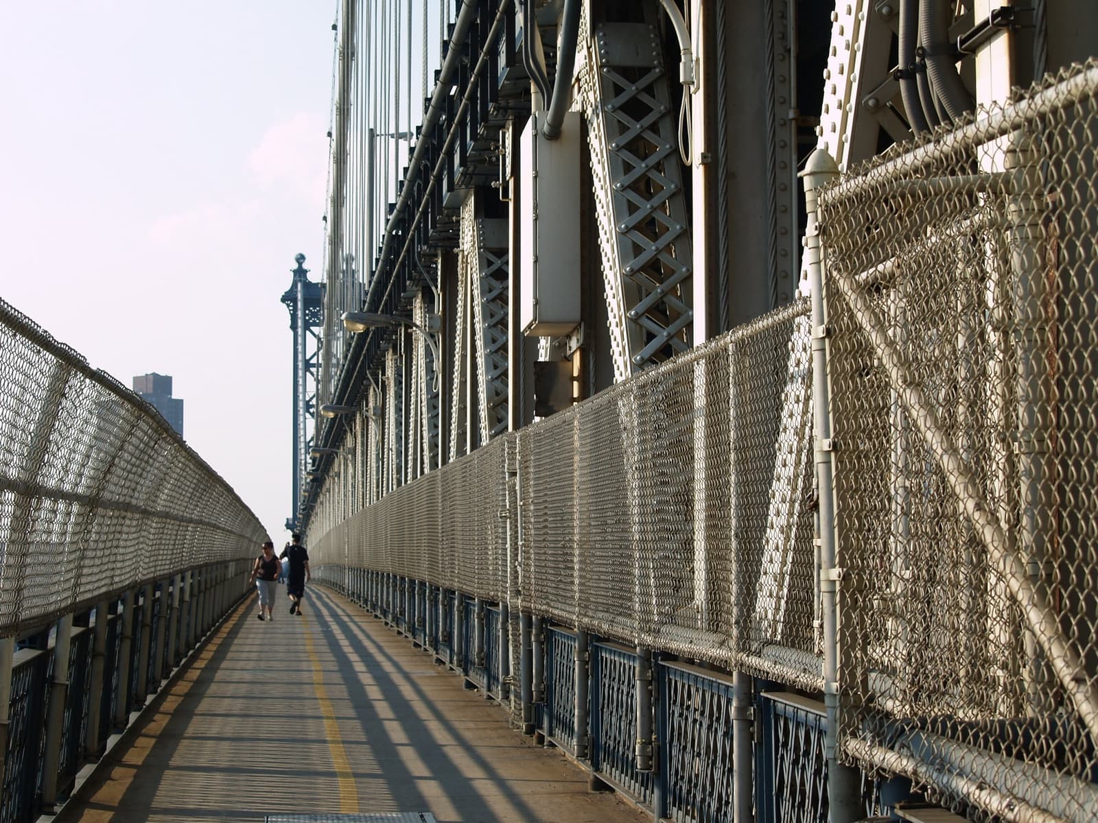 A fenced walkway along the side of a steel bridge