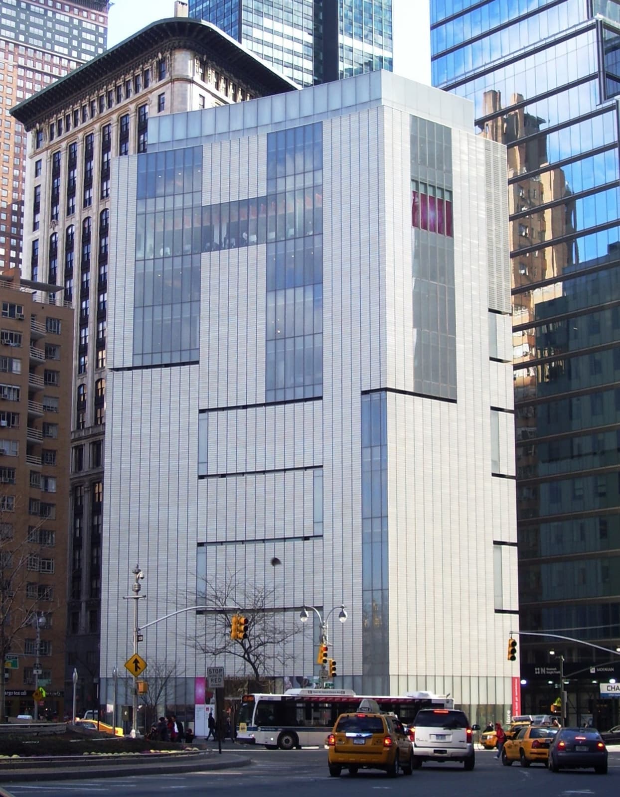 A white tiled tower on a corner, with taxis below