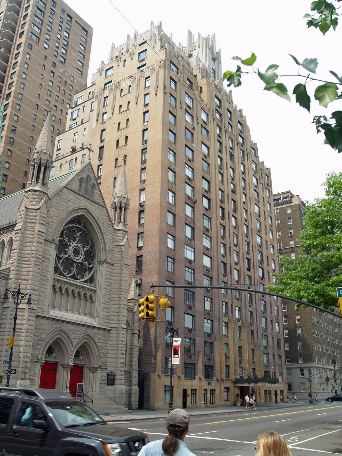 A tall Art Deco apartment tower with stepped upper floors, beside a church