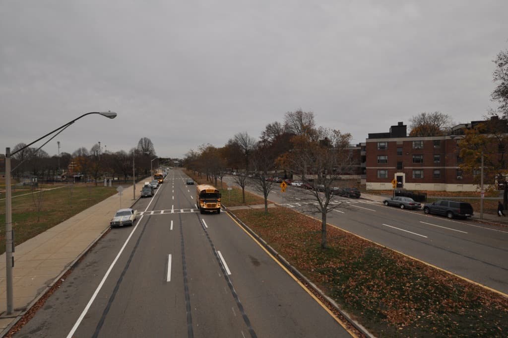 A city avenue with housing blocks and trees seen from a footbridge