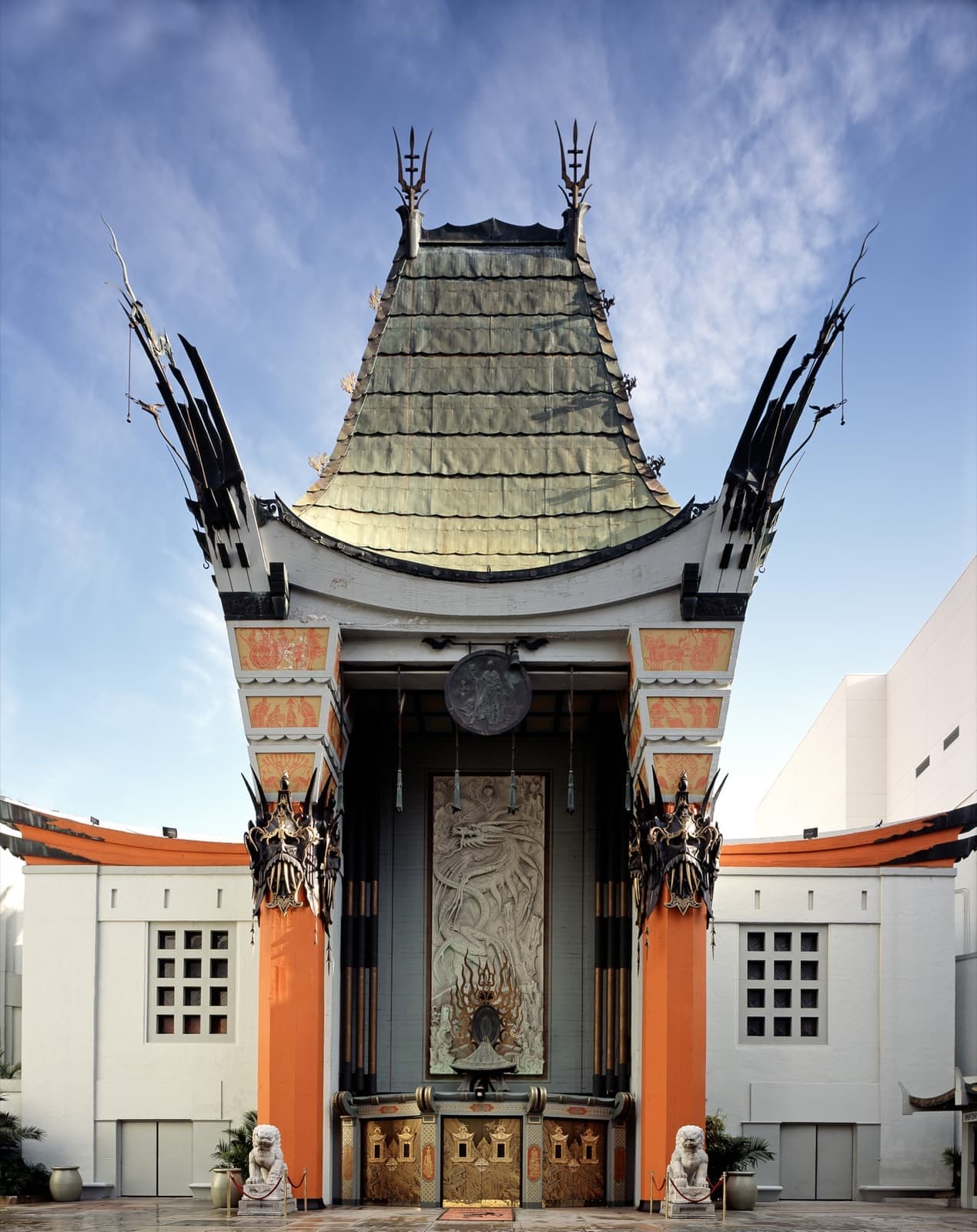 A theatre facade like a pagoda, with a green roof, red columns and a carved dragon