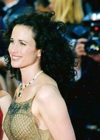 Andie MacDowell in 1998 with dark curly hair and a gold dress, smiling